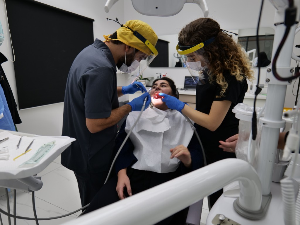 Dentist and assistant treating a patient in a bright Motif Clinic treatment room.