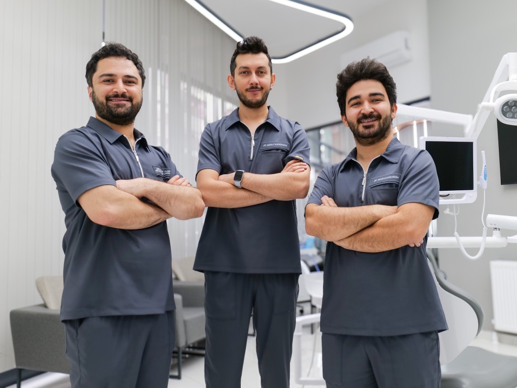 Three Motif Clinic dentists in grey scrubs standing together in the clinic.